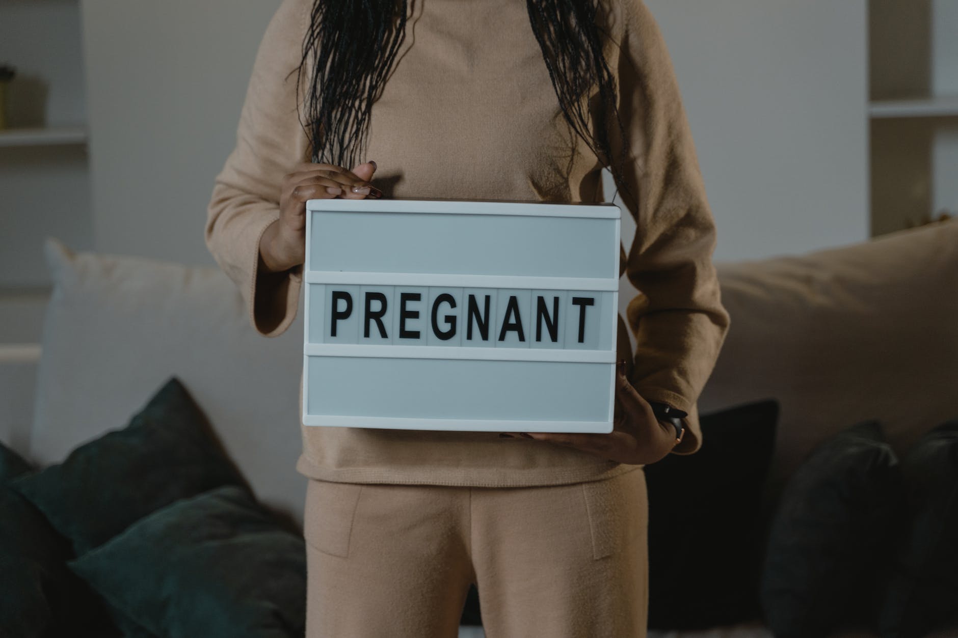 a woman holding a sign that says pregnant
