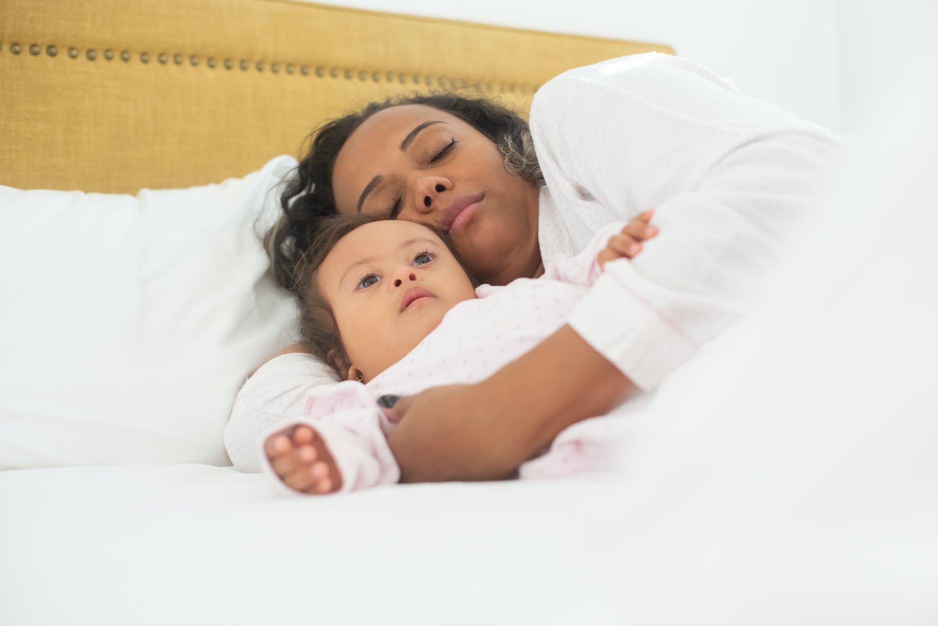 photograph of a mother sleeping with her daughter on a bed